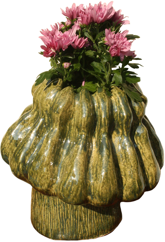 Decorative green vase with wavy texture holding pink flowers on a wooden surface.